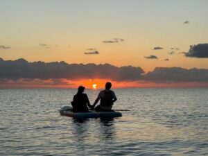 久米島の海で夕日と一緒にSUPを楽しむカップル
